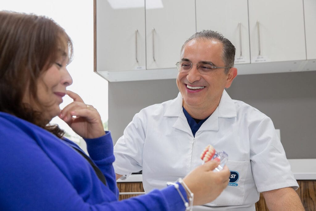 Dental Implant Patient Magalys Being Shown A Full Mouth Dental Implant Model By Dr. Abboud